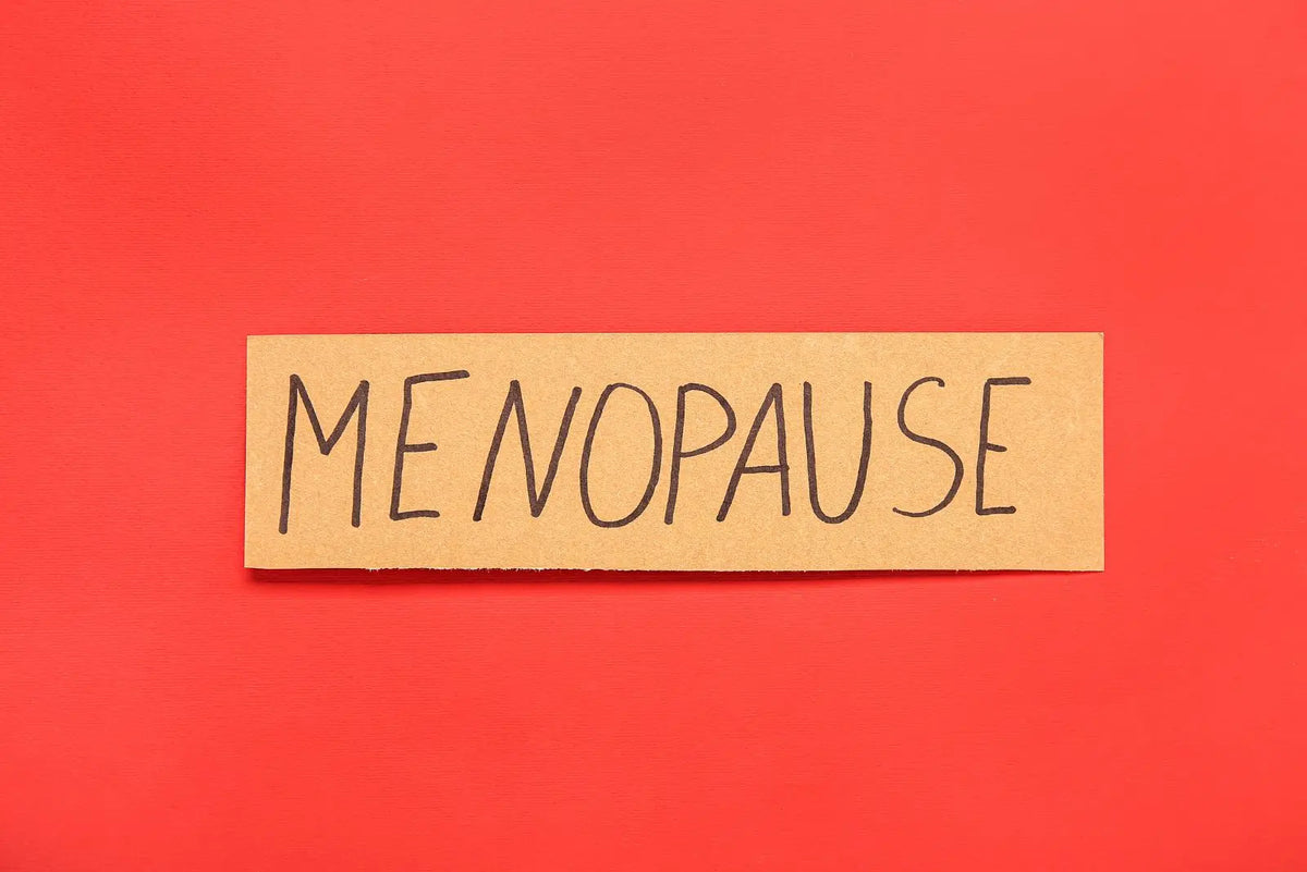 En lapp med ordet menopause mot röd bakgrund, klimakteriet